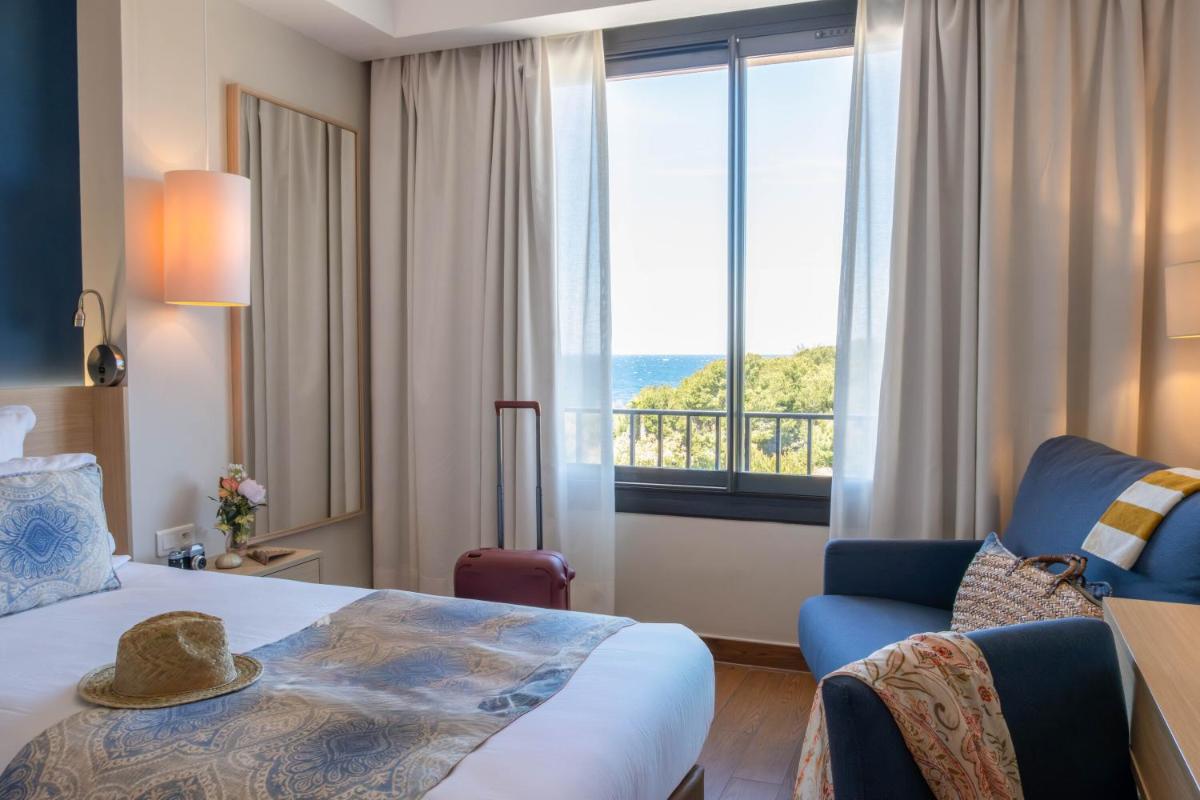 une chambre d'hôtel avec un lit et une grande fenêtre dans l'établissement Hôtel Helios & SPA - Ile des Embiez, à Six-Fours-les-Plages