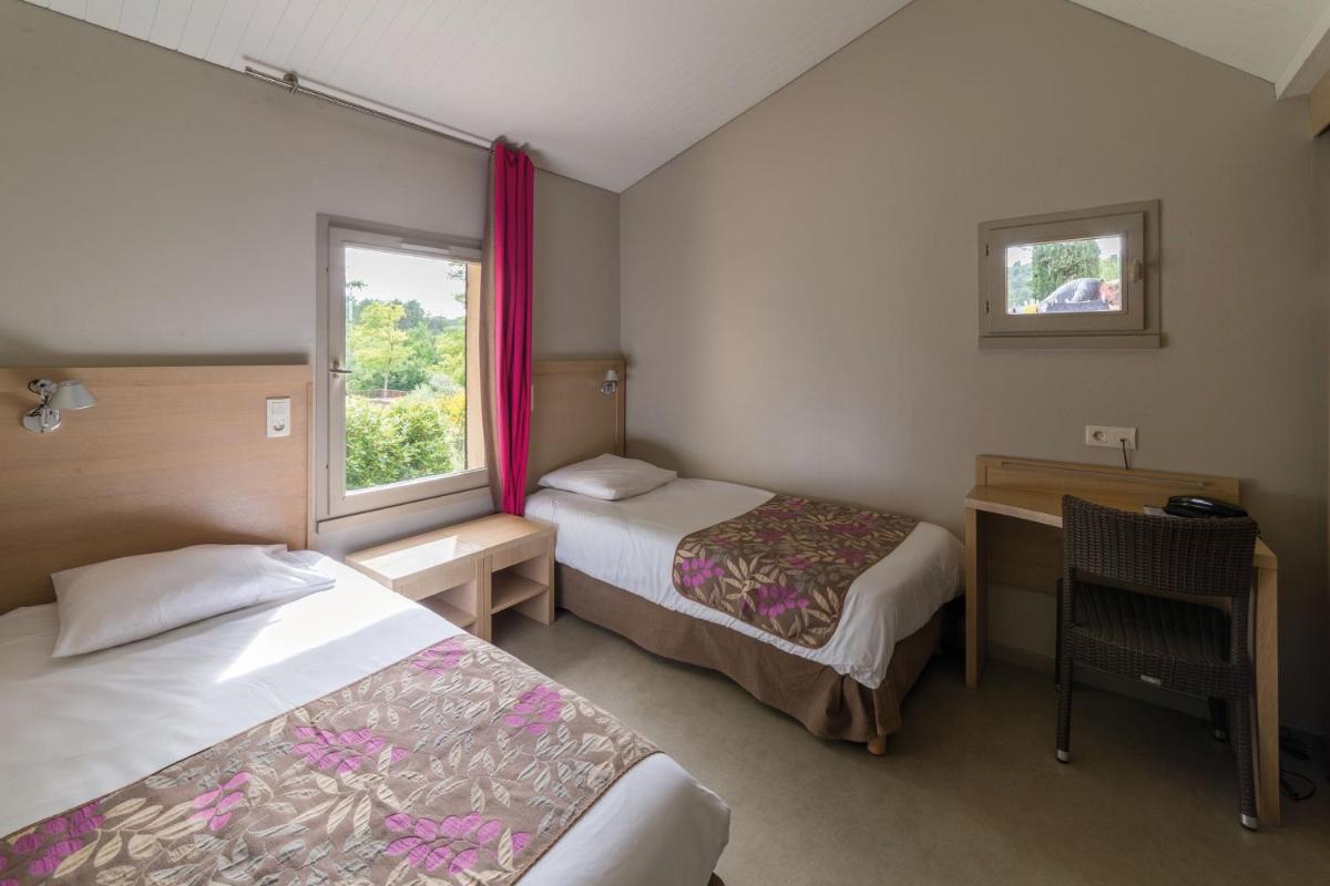 une chambre avec deux lits, un bureau et une fenêtre dans l'établissement Club Vacances Bleues Domaine de Château Laval, à Gréoux-les-Bains