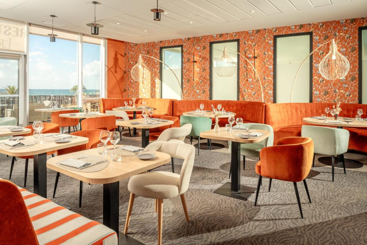 un restaurant avec des tables, des chaises et des fenêtres dans l'établissement Hôtel de la Baie - Thalassothérapie PREVITHAL, à Donville-les-Bains