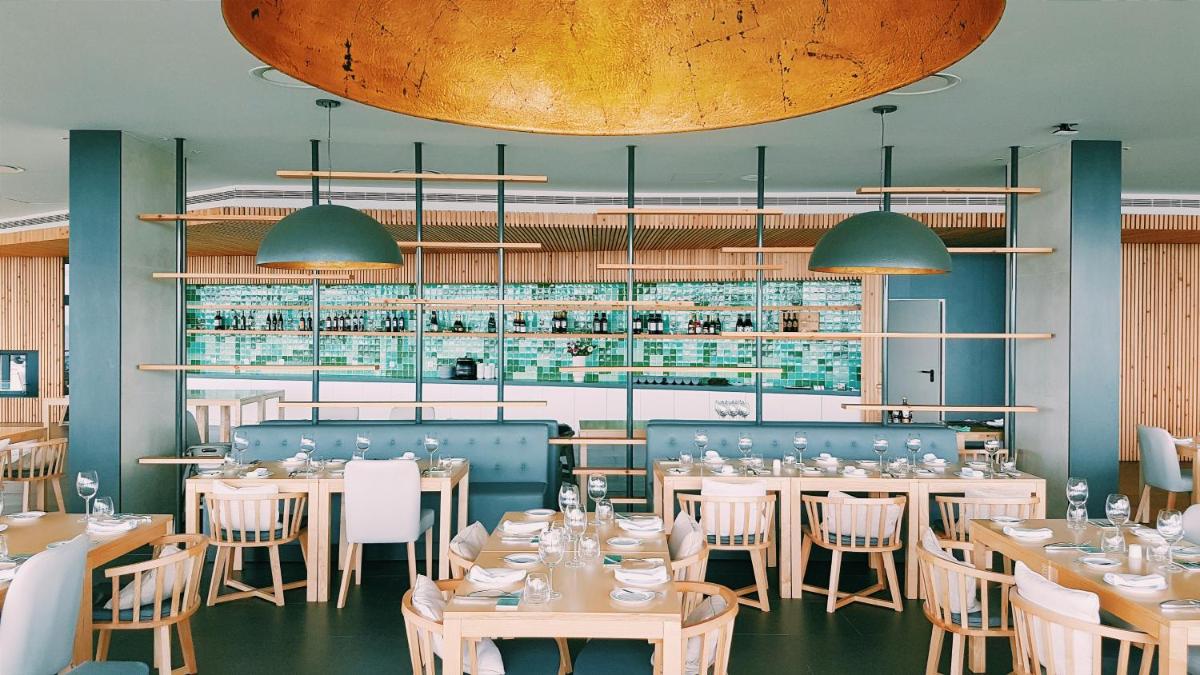 um restaurante com mesas e cadeiras e um bar em Pedras do Mar Resort & Spa em Fenais da Luz