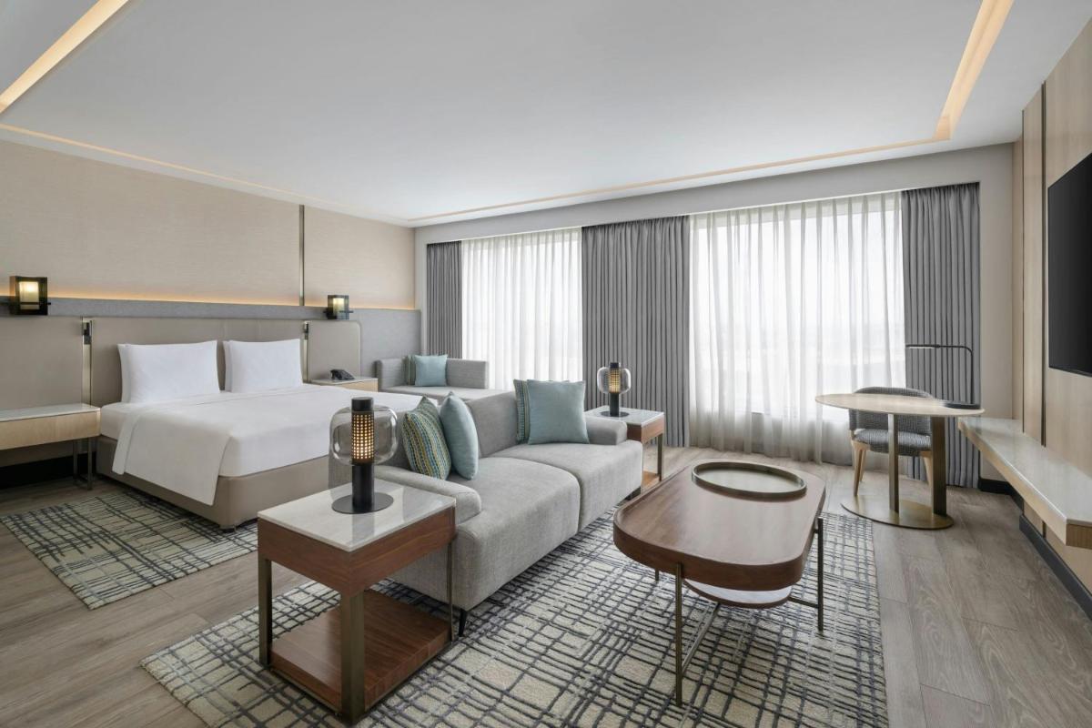 a hotel room with a bed and a couch at Courtyard by Marriott Mumbai International Airport in Mumbai a hotel room with a bed and a couch at Courtyard by Marriott Mumbai International Airport in Mumbai
