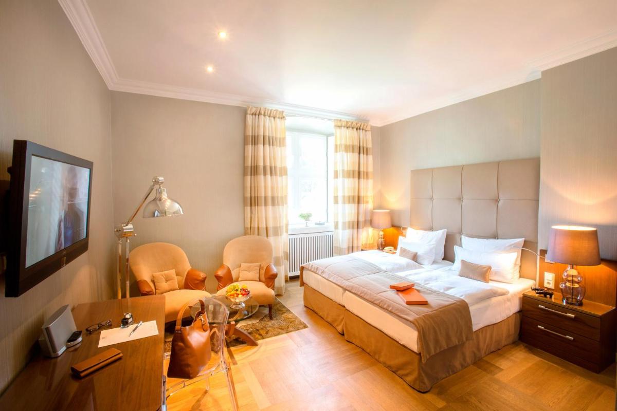 ein Schlafzimmer mit einem Bett, einem Stuhl und einem Schreibtisch in der Unterkunft Schlosshotel Hugenpoet in Essen