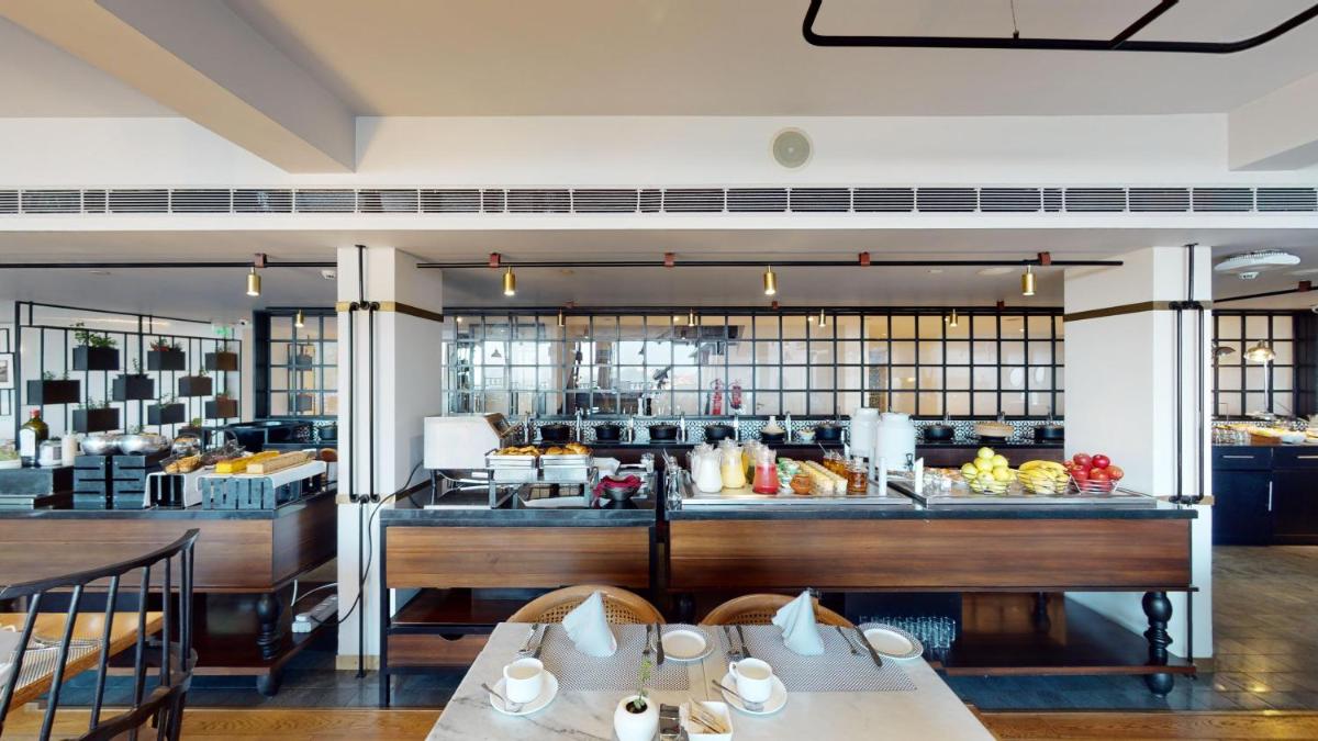 a restaurant with tables in front of a kitchen at Radisson Hotel Shimla in Shimla