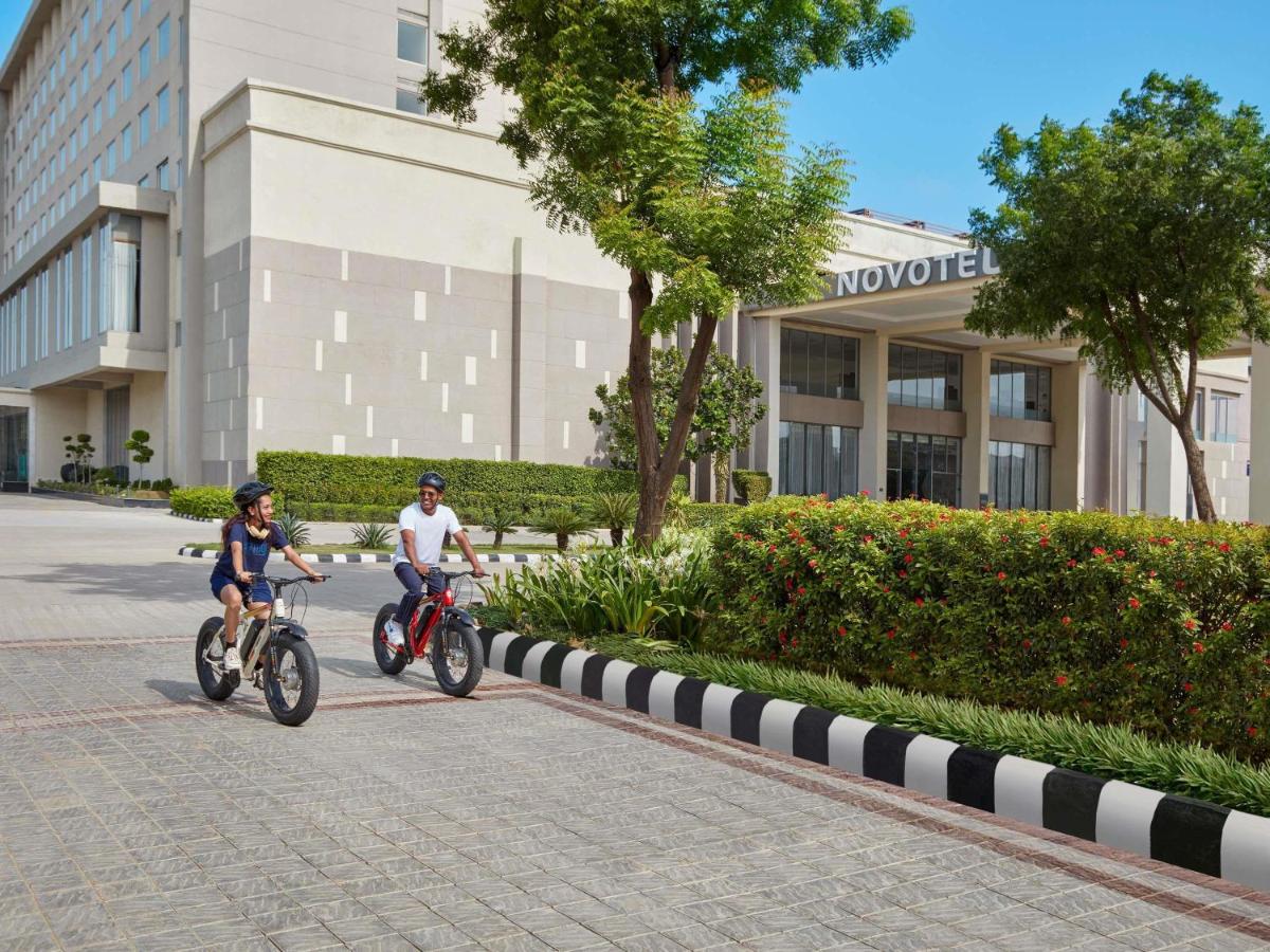 two people riding bikes in front of a building at Novotel Jaipur Convention Centre in Jaipur
