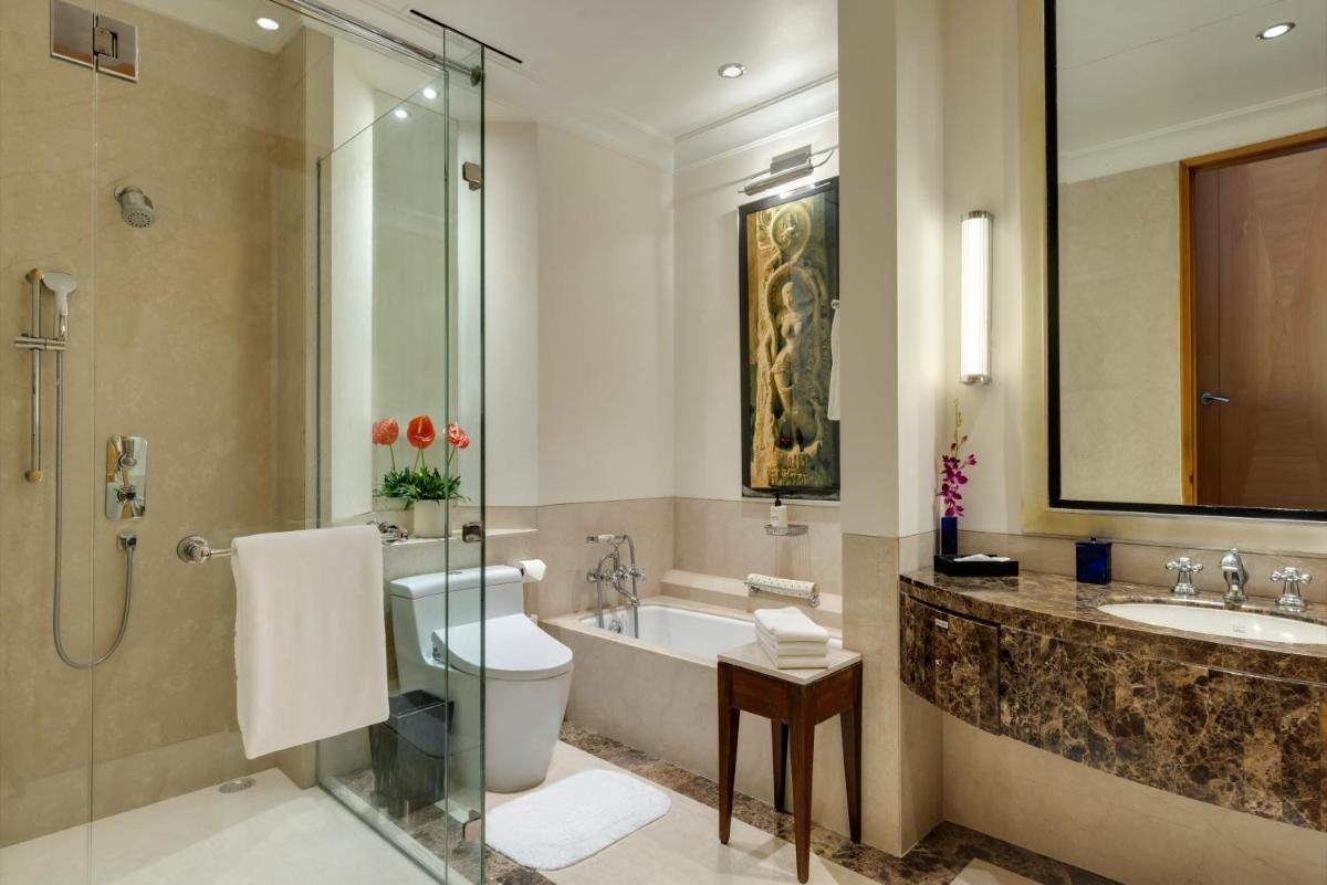 a bathroom with a toilet and a tub and a sink at Trident Gurgaon in Gurgaon