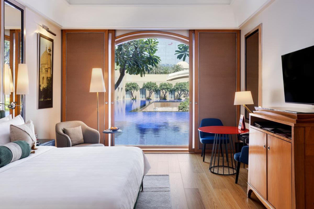 a hotel room with a bed and a view of a pool at Trident Gurgaon in Gurgaon