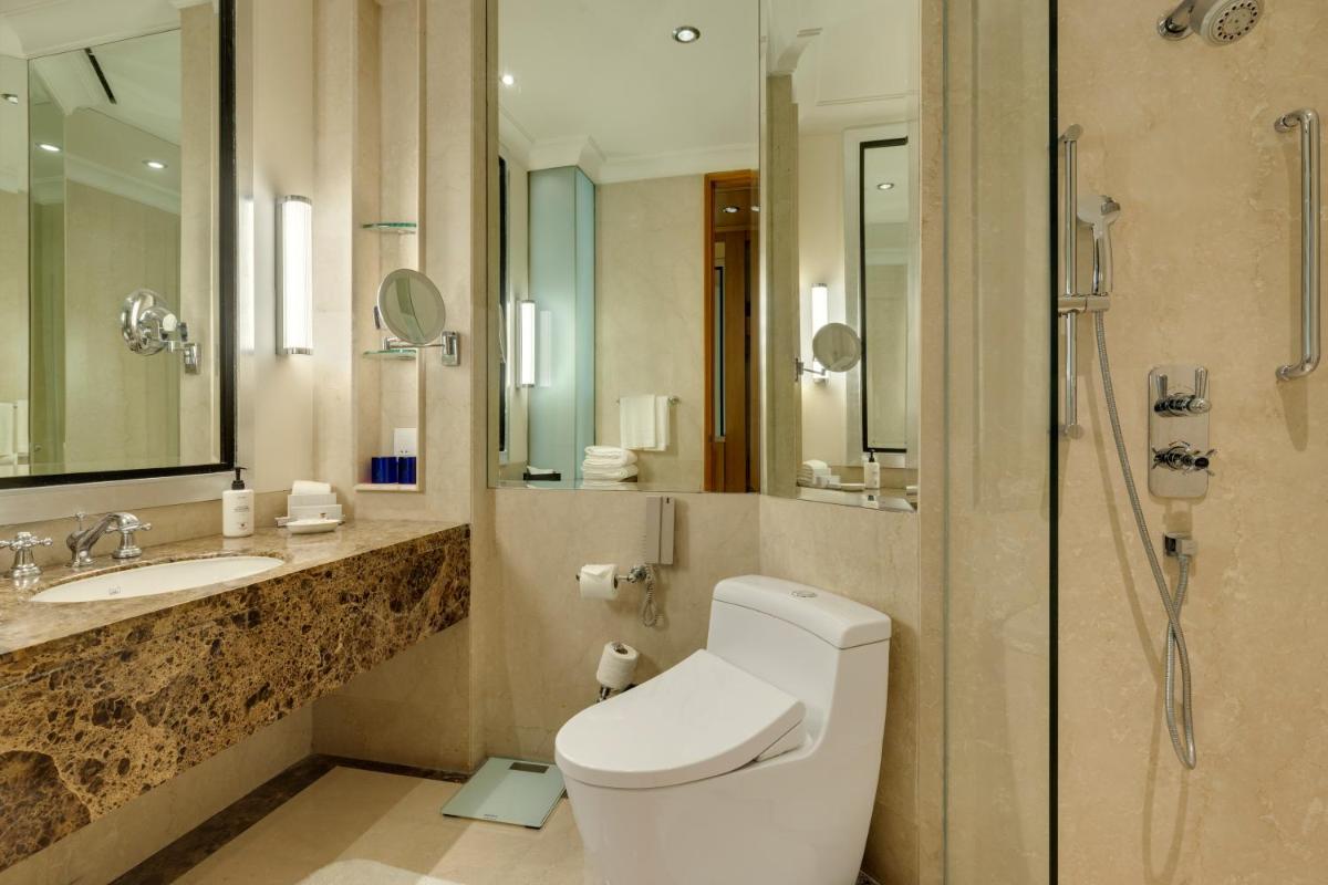 a bathroom with a toilet and a sink and a shower at Trident Gurgaon in Gurgaon