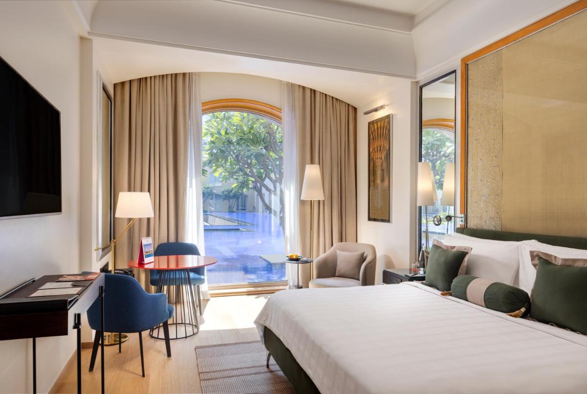 a hotel room with a large bed and a desk at Trident Gurgaon in Gurgaon