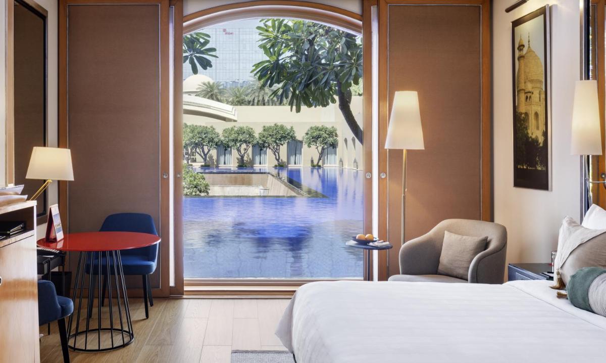 a hotel room with a view of a pool through a window at Trident Gurgaon in Gurgaon