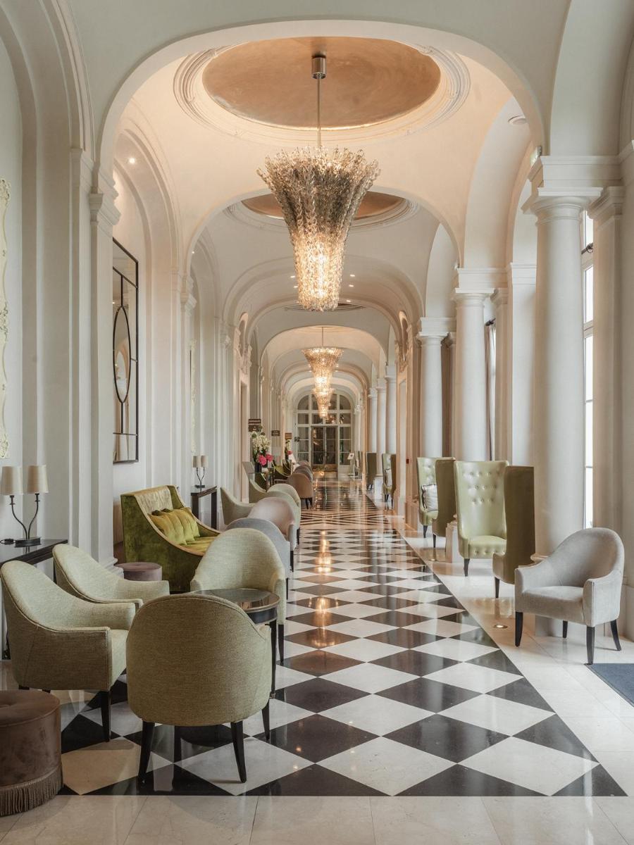 un hall d'entrée avec des chaises et un sol en damier dans l'établissement Waldorf Astoria Versailles - Trianon Palace, à Versailles