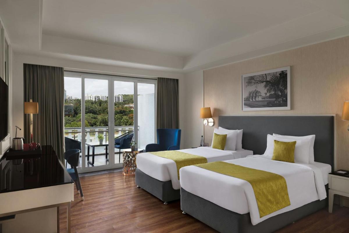 a hotel room with two beds and a balcony at Amanora The Fern Pune, Series by Marriott in Pune