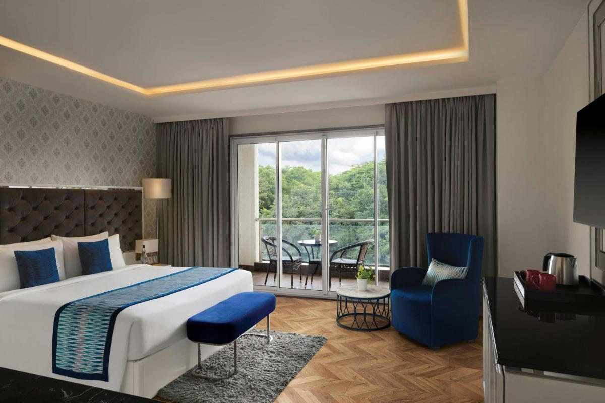 a hotel room with a bed and a chair and a window at Amanora The Fern Pune, Series by Marriott in Pune