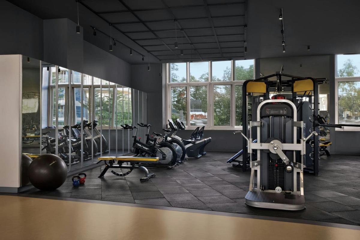 a gym with treadmills and exercise equipment and windows at Amanora The Fern Pune, Series by Marriott in Pune