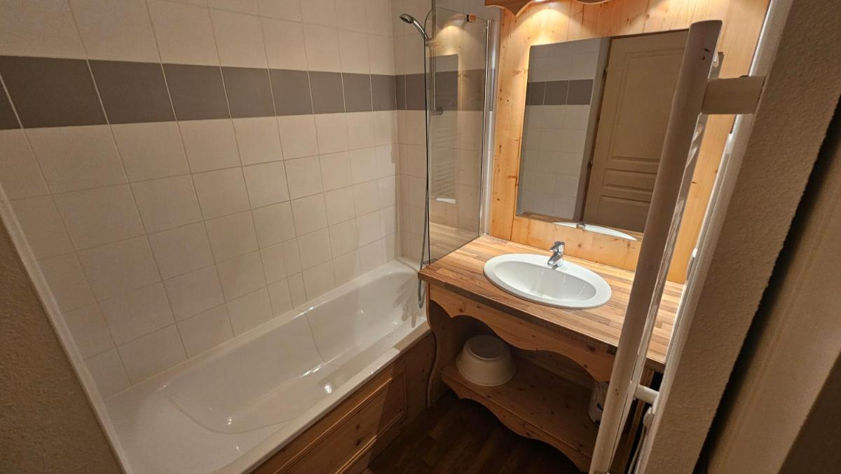 une salle de bains avec lavabo, baignoire et miroir dans l'établissement Résidence Orelle 3 vallées by AltiResid, à Orelle