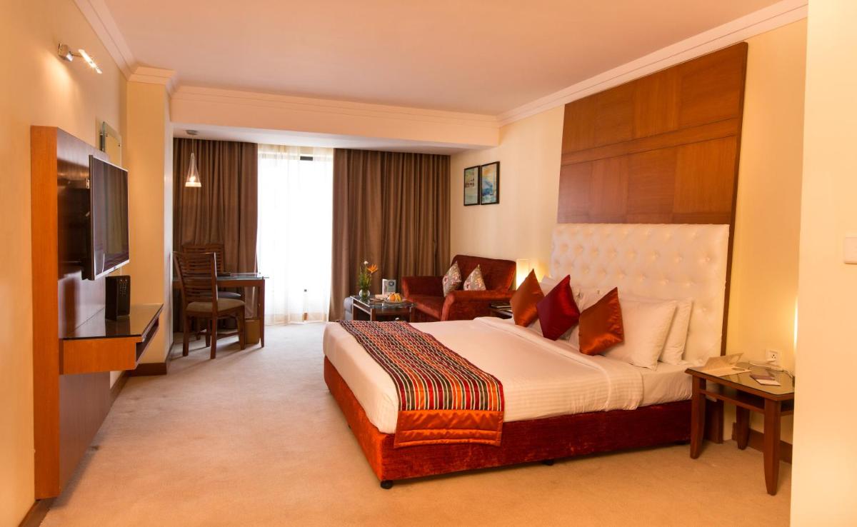 a hotel room with a large bed and a television at The Chancery Pavilion in Bengaluru