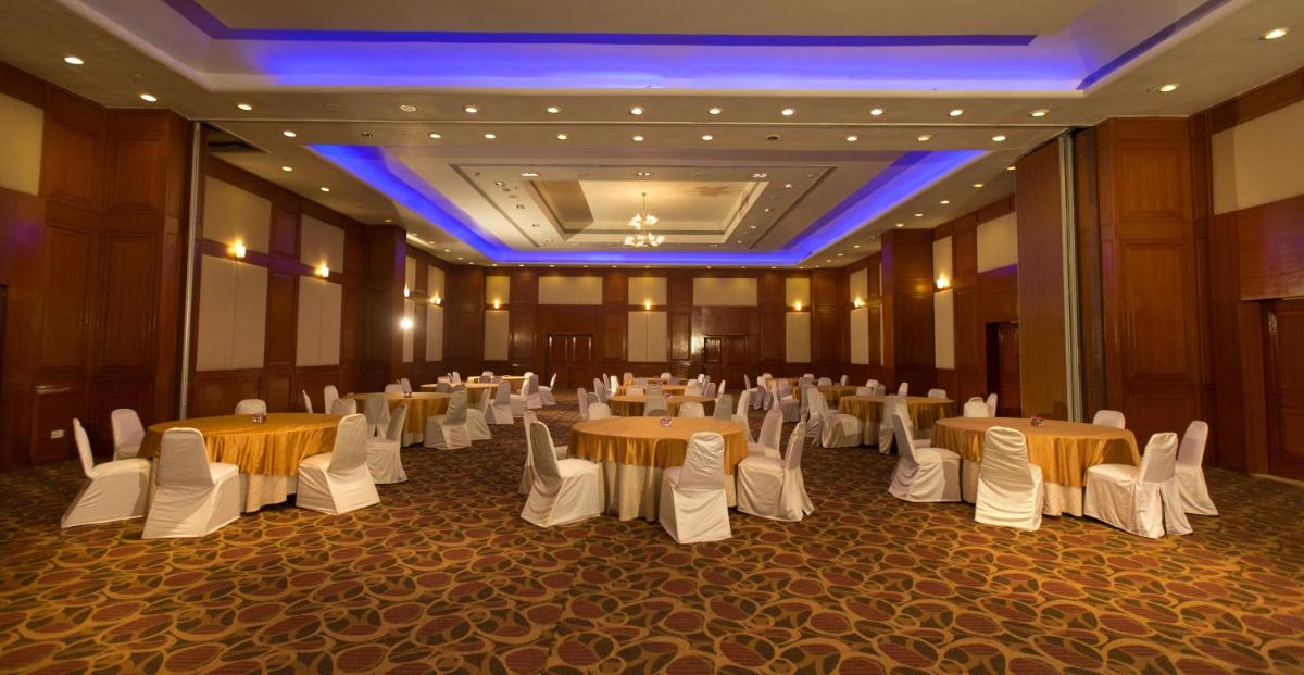 a banquet hall with white tables and white chairs at The Chancery Pavilion in Bengaluru