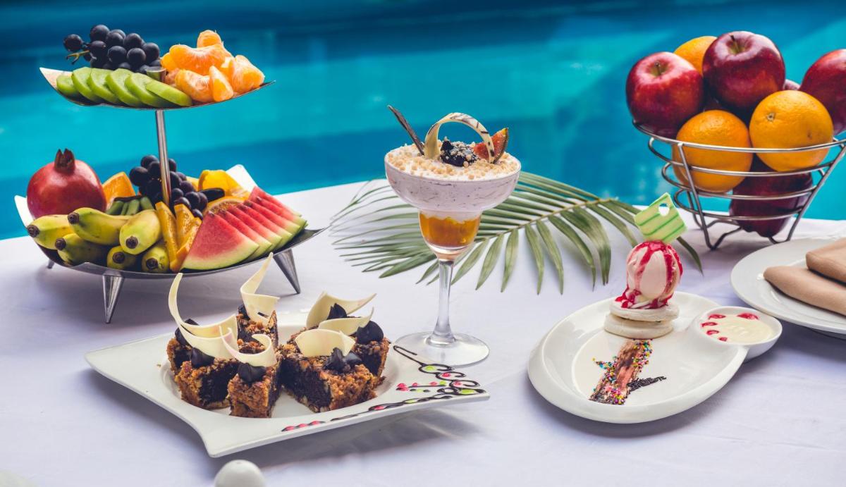 a table topped with desserts and fruit on plates at The Chancery Pavilion in Bengaluru