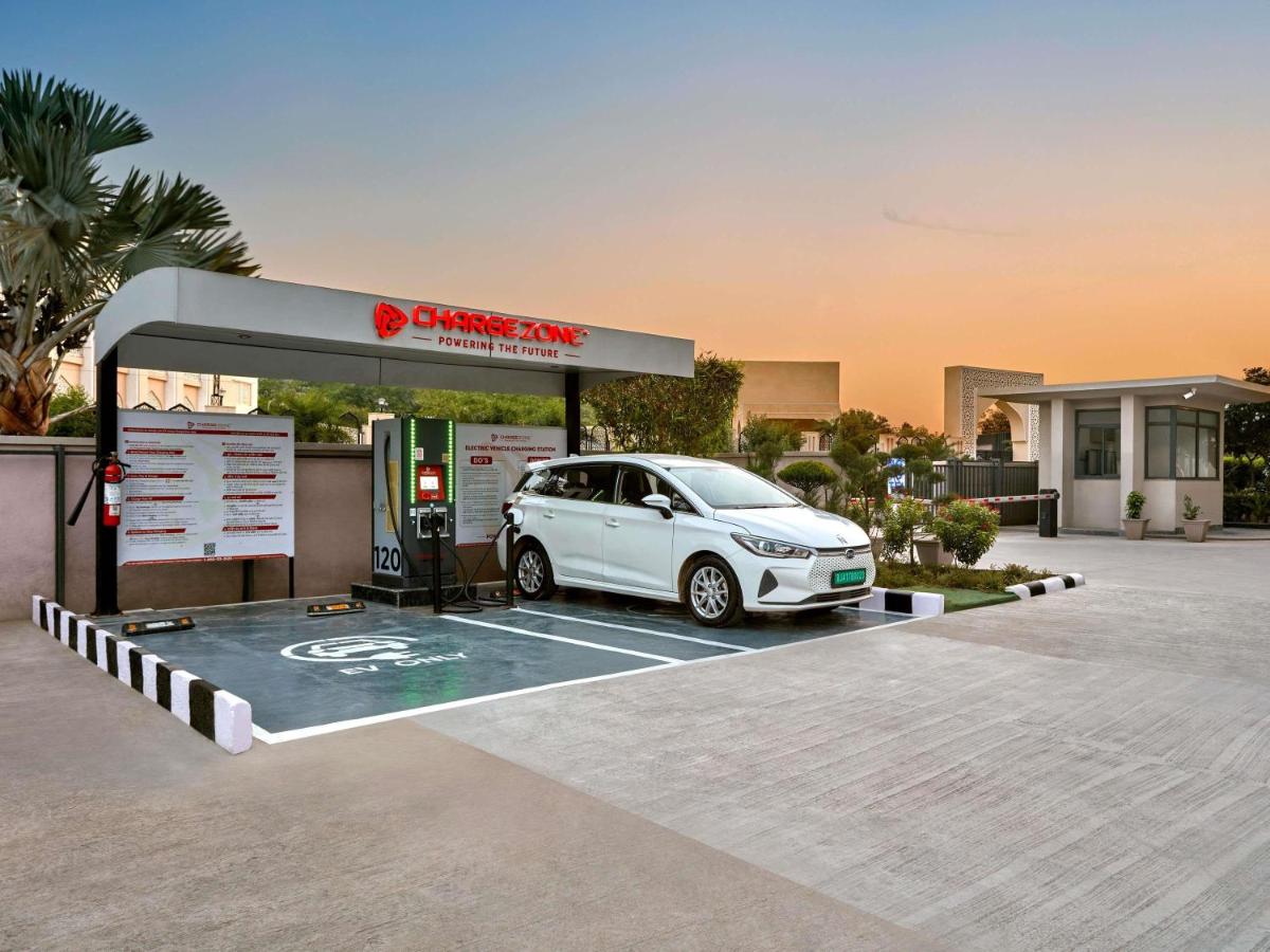 a white car is parked at a gas station at Novotel Jaipur Convention Centre in Jaipur