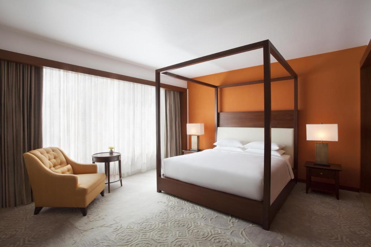 a bedroom with a canopy bed and a chair at Park Hyatt Chennai in Chennai