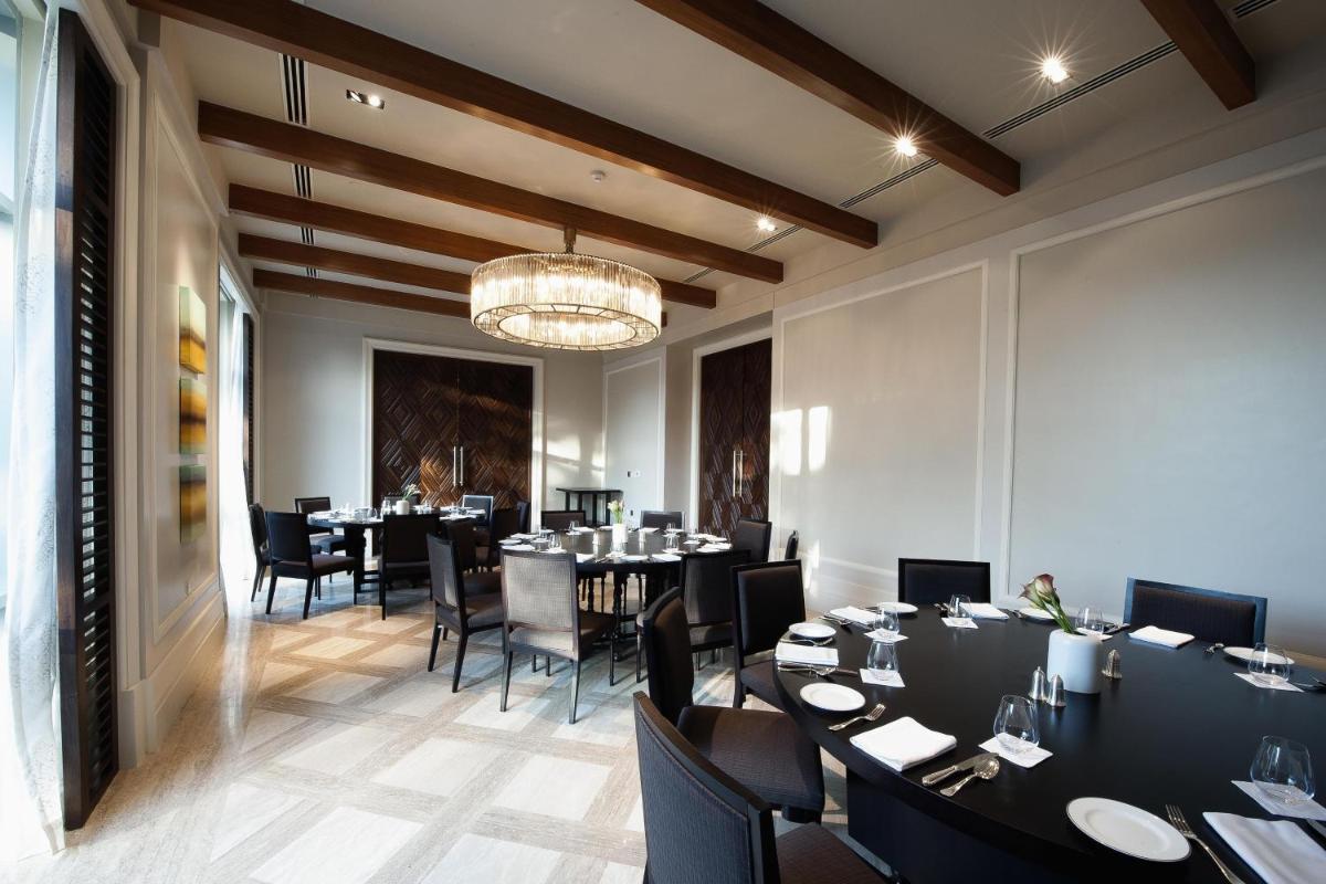 a dining room with tables and chairs and a chandelier at Park Hyatt Chennai in Chennai