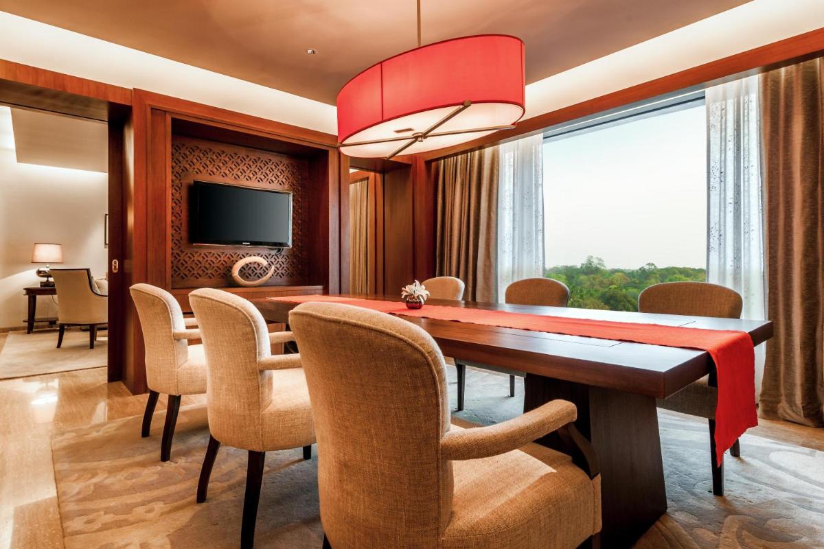 a dining room with a table and chairs and a television at Park Hyatt Chennai in Chennai