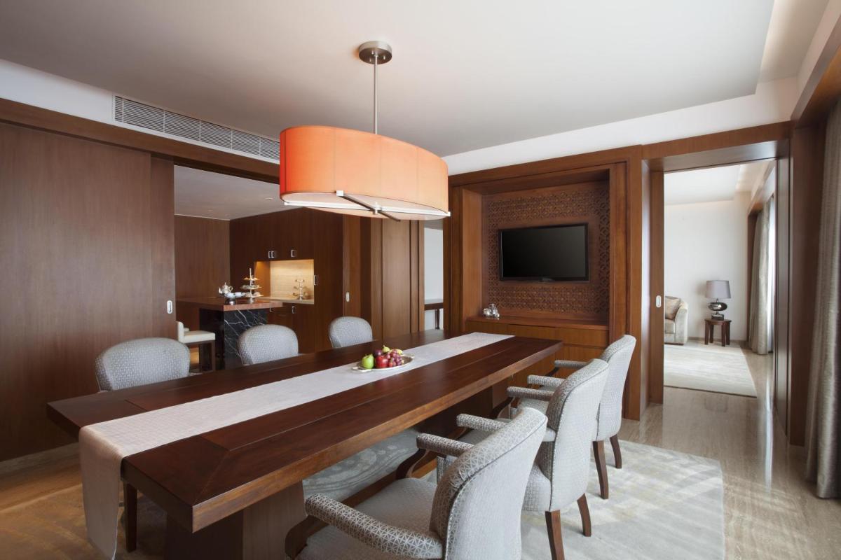 a dining room with a wooden table and white chairs at Park Hyatt Chennai in Chennai