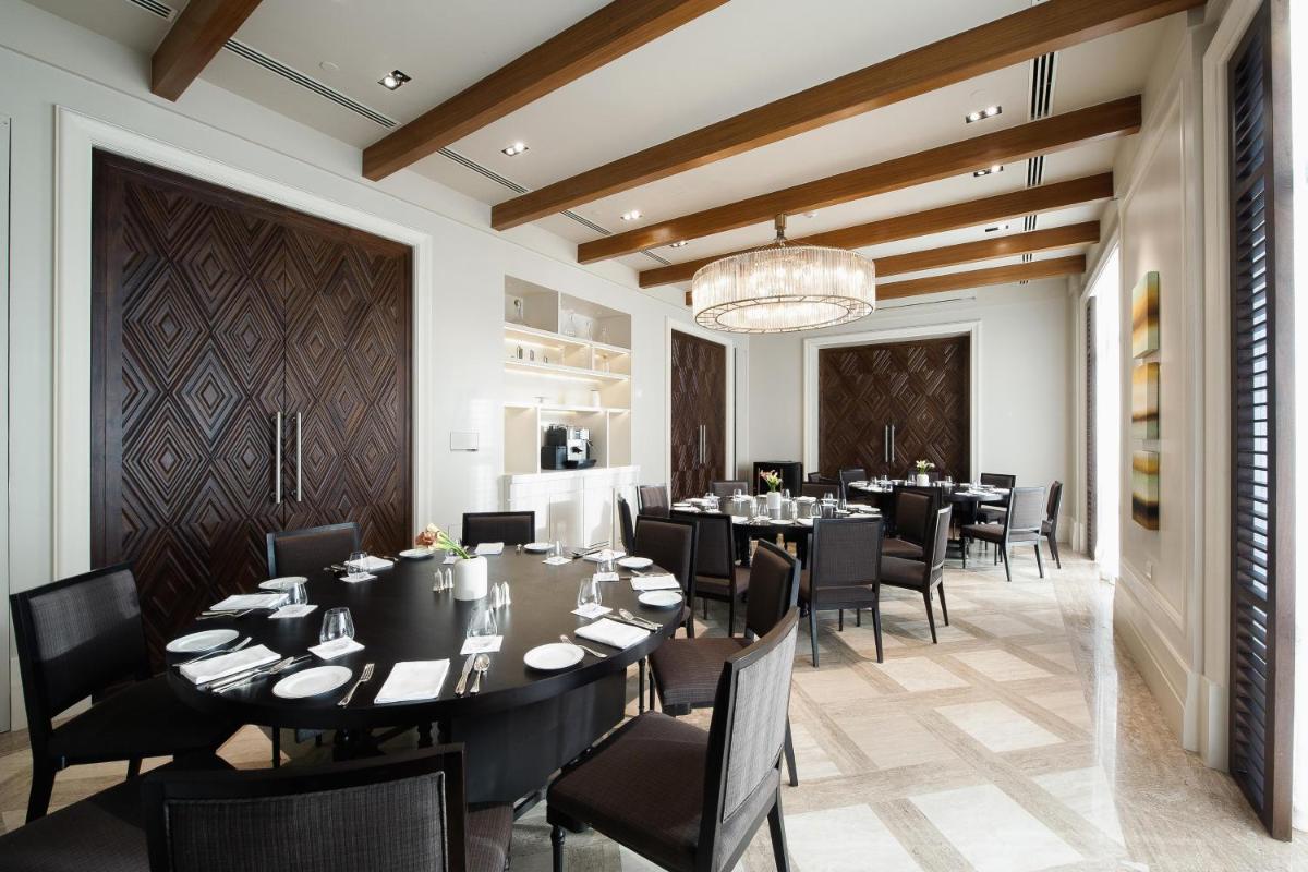 a dining room with tables and chairs and a chandelier at Park Hyatt Chennai in Chennai
