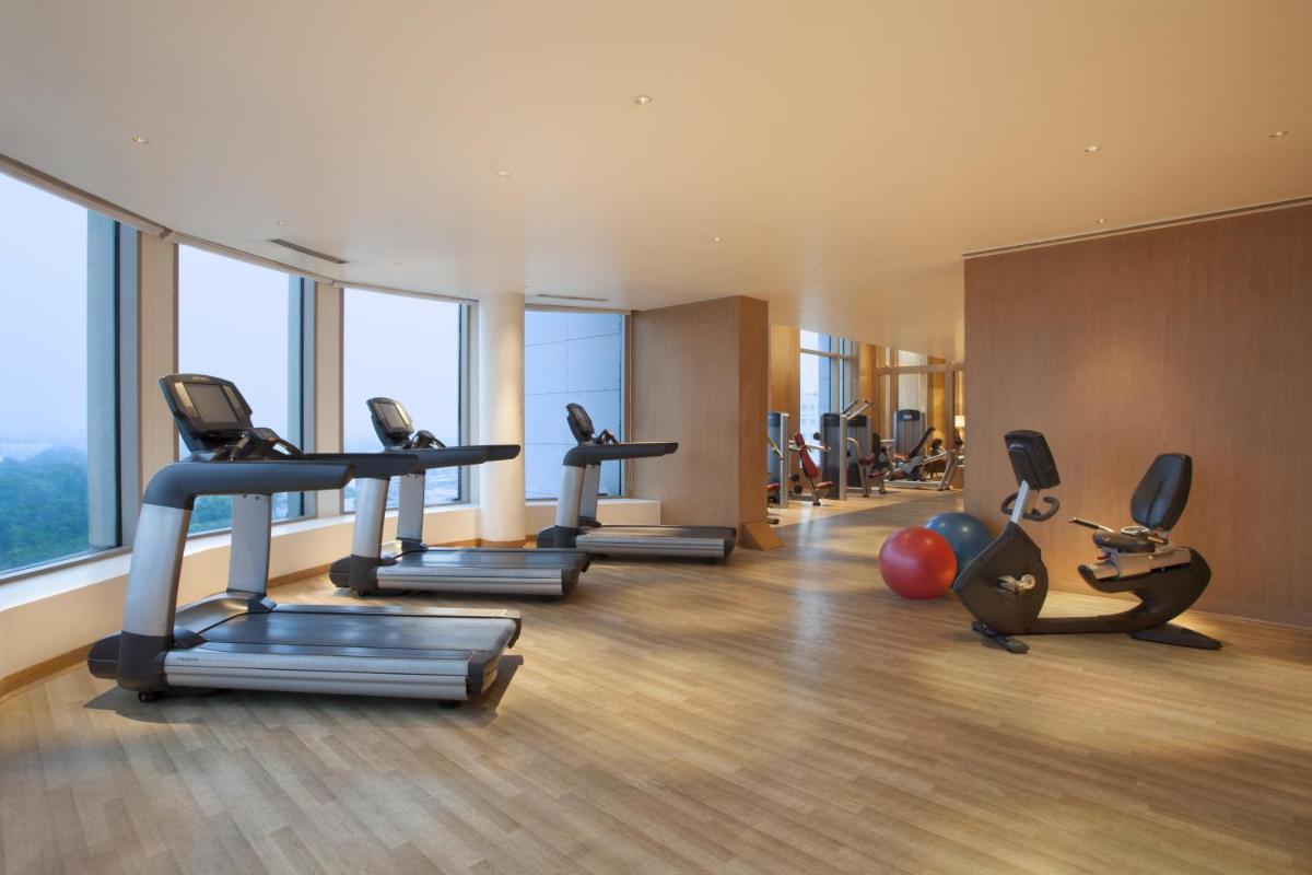 a gym with treadmills and exercise equipment in a building at Park Hyatt Chennai in Chennai