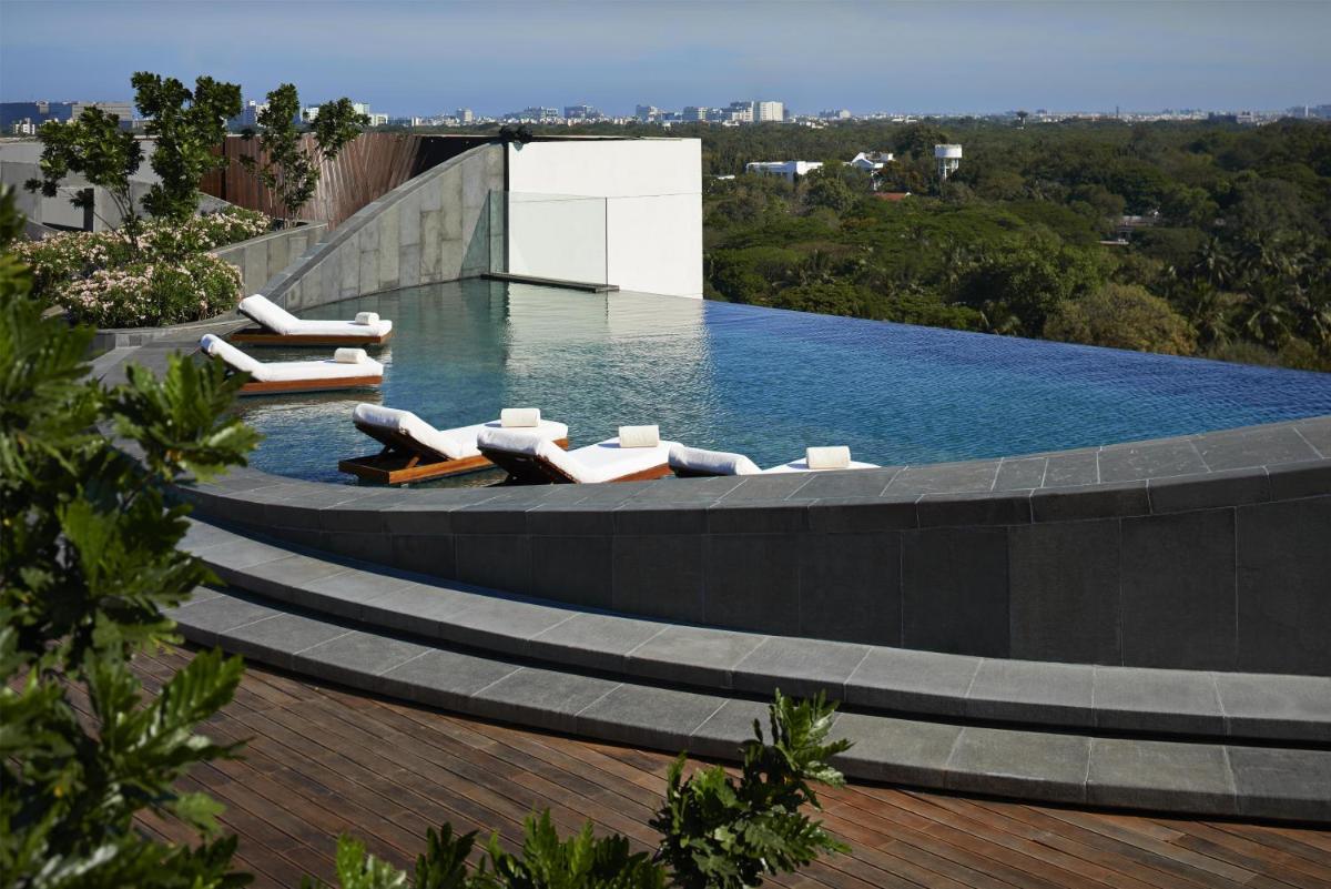 a swimming pool with lounge chairs on top of a building at Park Hyatt Chennai in Chennai
