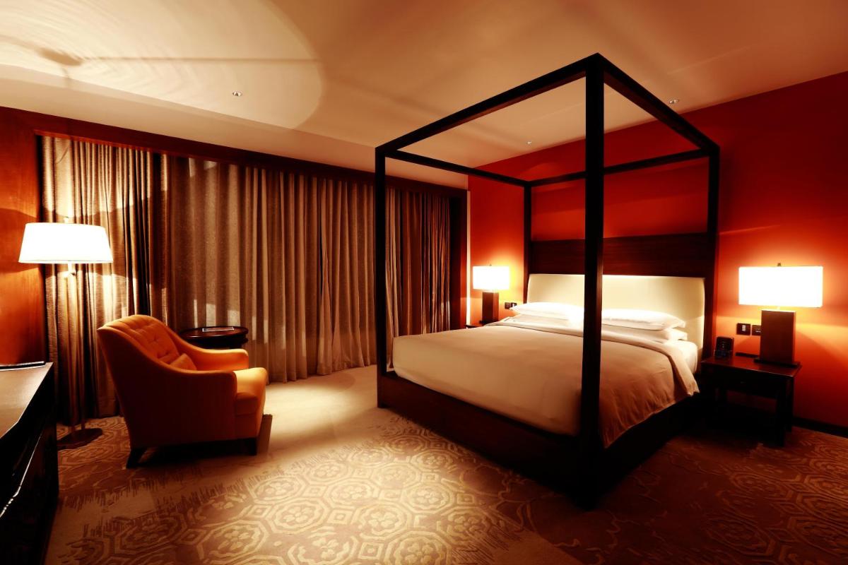 a bedroom with a canopy bed and a chair at Park Hyatt Chennai in Chennai
