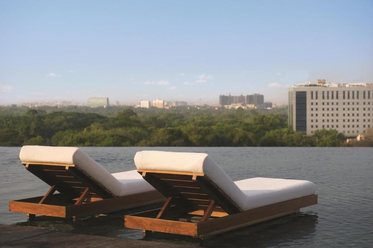 two lounge chairs sitting on a dock in the water at Park Hyatt Chennai in Chennai