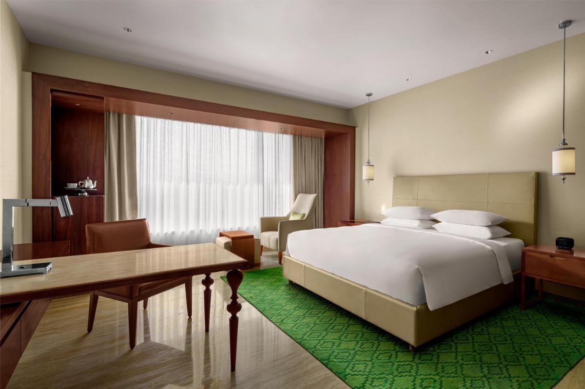 a bedroom with a large bed and a desk and a desk at Park Hyatt Chennai in Chennai