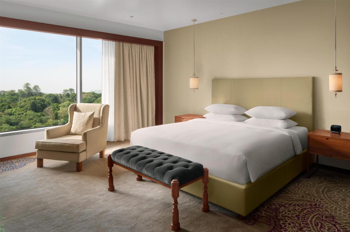 a bedroom with a bed and a chair and a window at Park Hyatt Chennai in Chennai