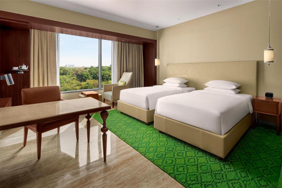 a hotel room with two beds and a desk at Park Hyatt Chennai in Chennai