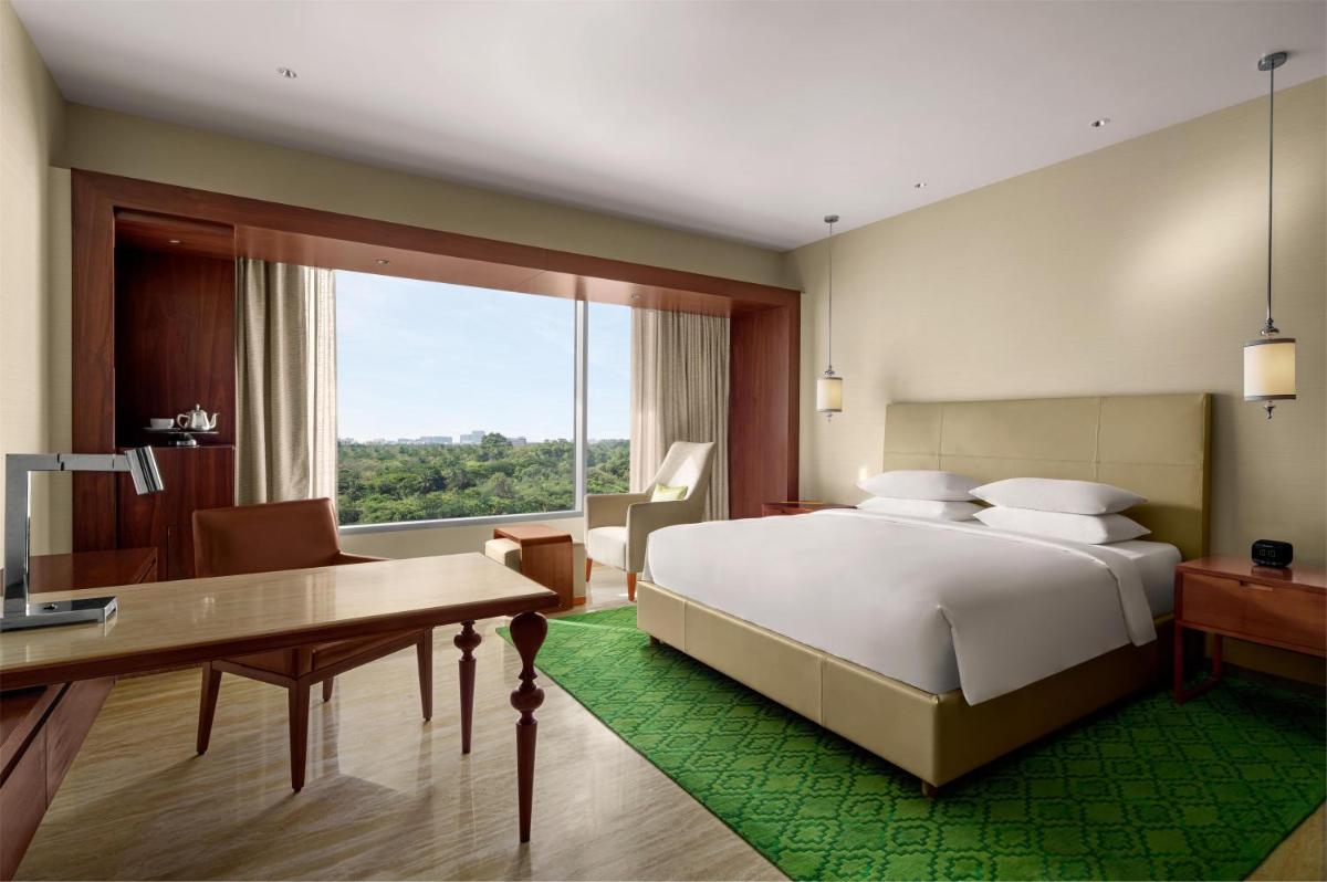 a bedroom with a bed and a desk and a window at Park Hyatt Chennai in Chennai