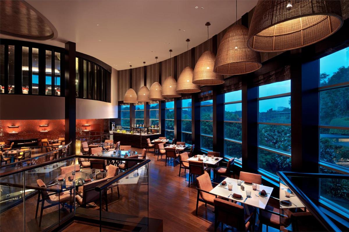 a restaurant with tables and chairs and large windows at Park Hyatt Chennai in Chennai