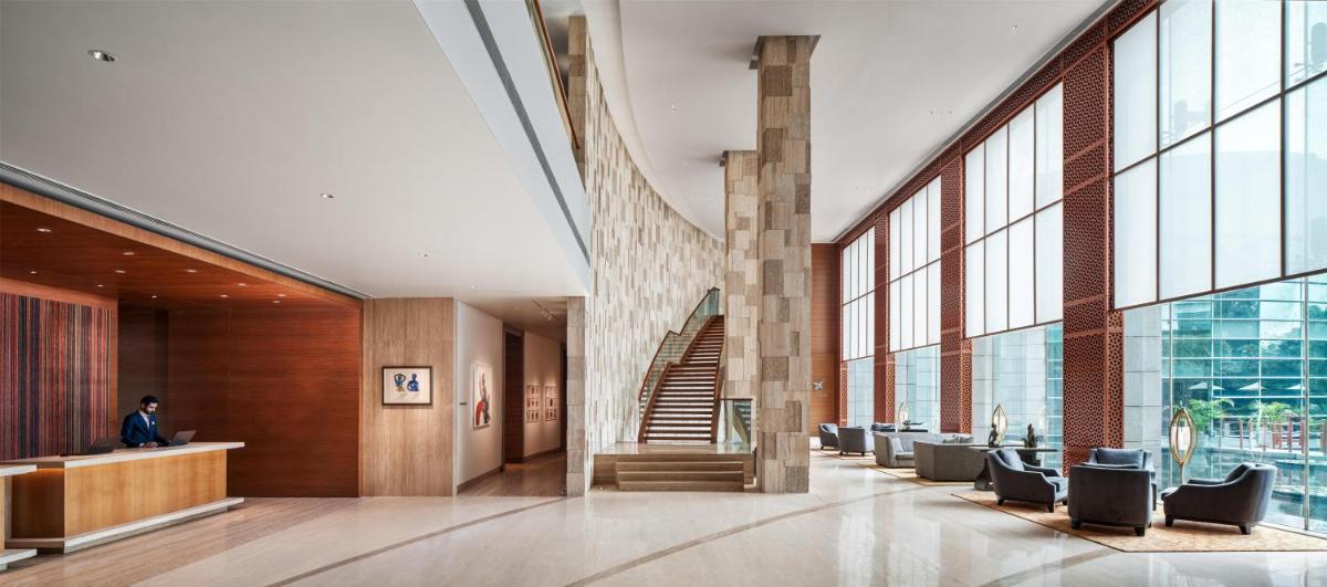 a lobby of a building with a staircase and chairs at Park Hyatt Chennai in Chennai