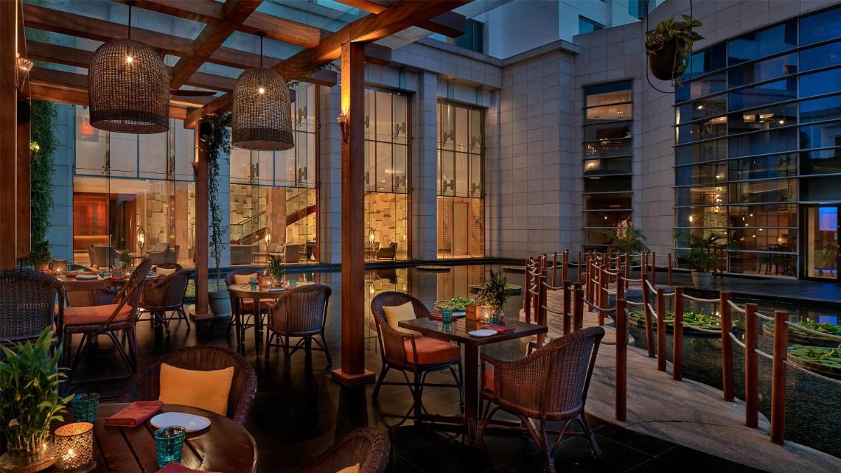 a restaurant with tables and chairs on a balcony at Park Hyatt Chennai in Chennai