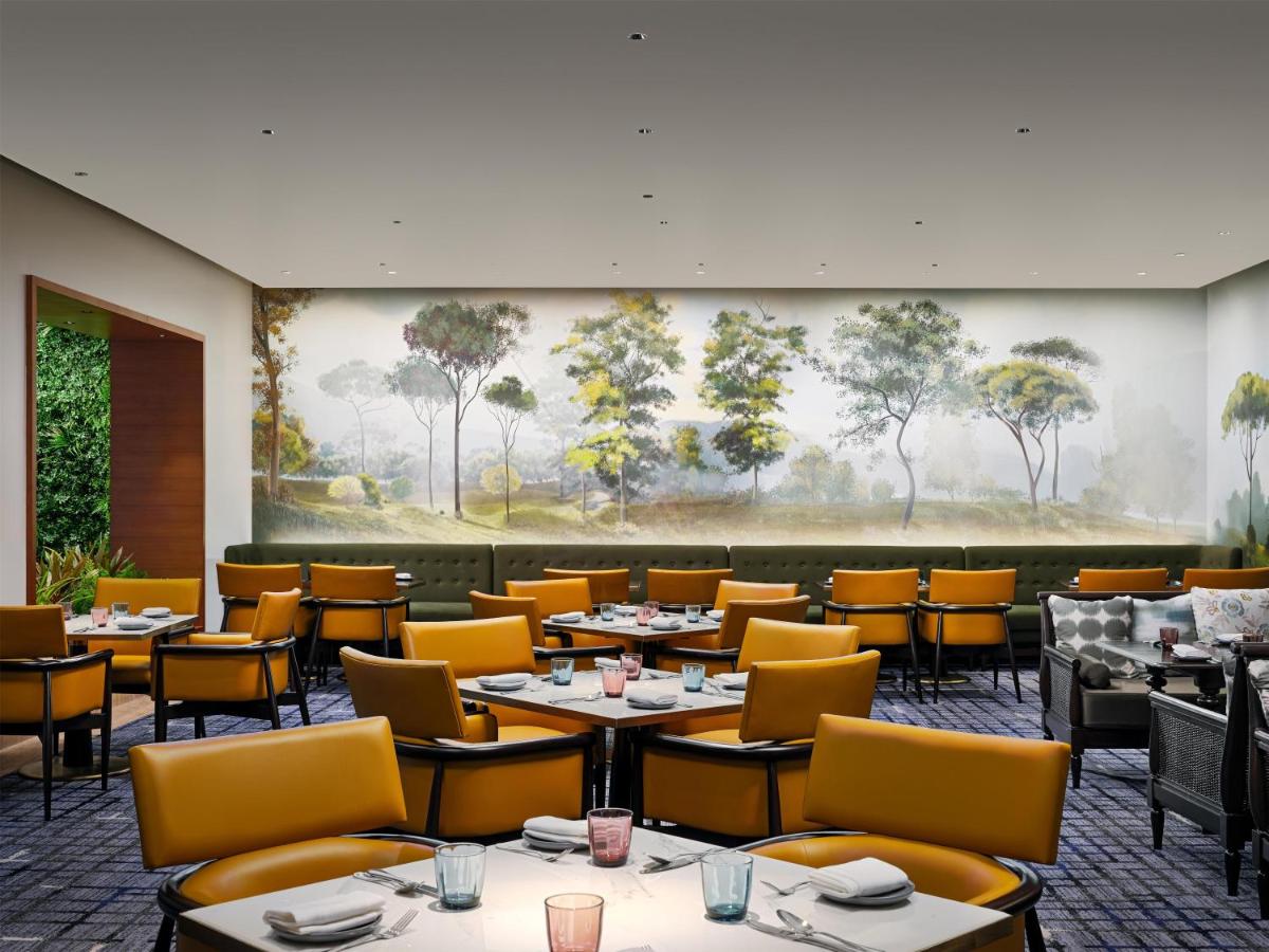a dining room with tables and chairs and a painting at Park Hyatt Chennai in Chennai