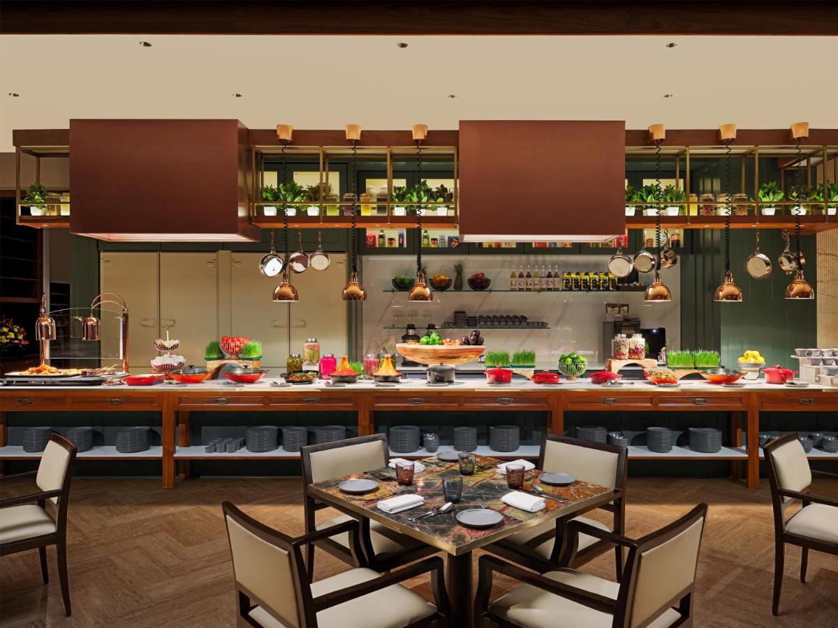 a restaurant with a table and chairs and a kitchen at Park Hyatt Chennai in Chennai