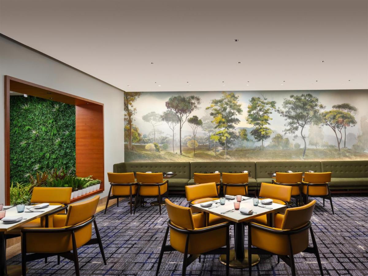a dining room with tables and chairs and a painting at Park Hyatt Chennai in Chennai