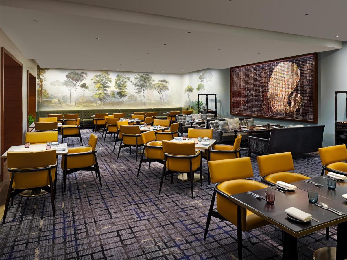 a dining room with tables and yellow chairs at Park Hyatt Chennai in Chennai