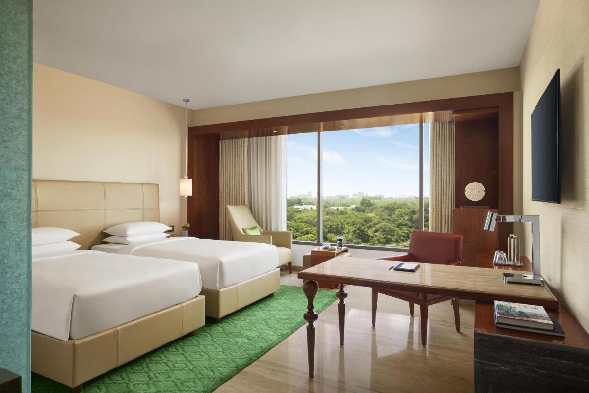a hotel room with two beds and a desk at Park Hyatt Chennai in Chennai