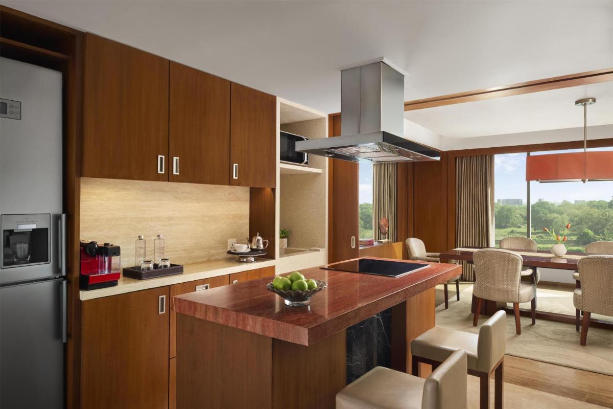 a kitchen with wooden cabinets and a dining room with a table at Park Hyatt Chennai in Chennai