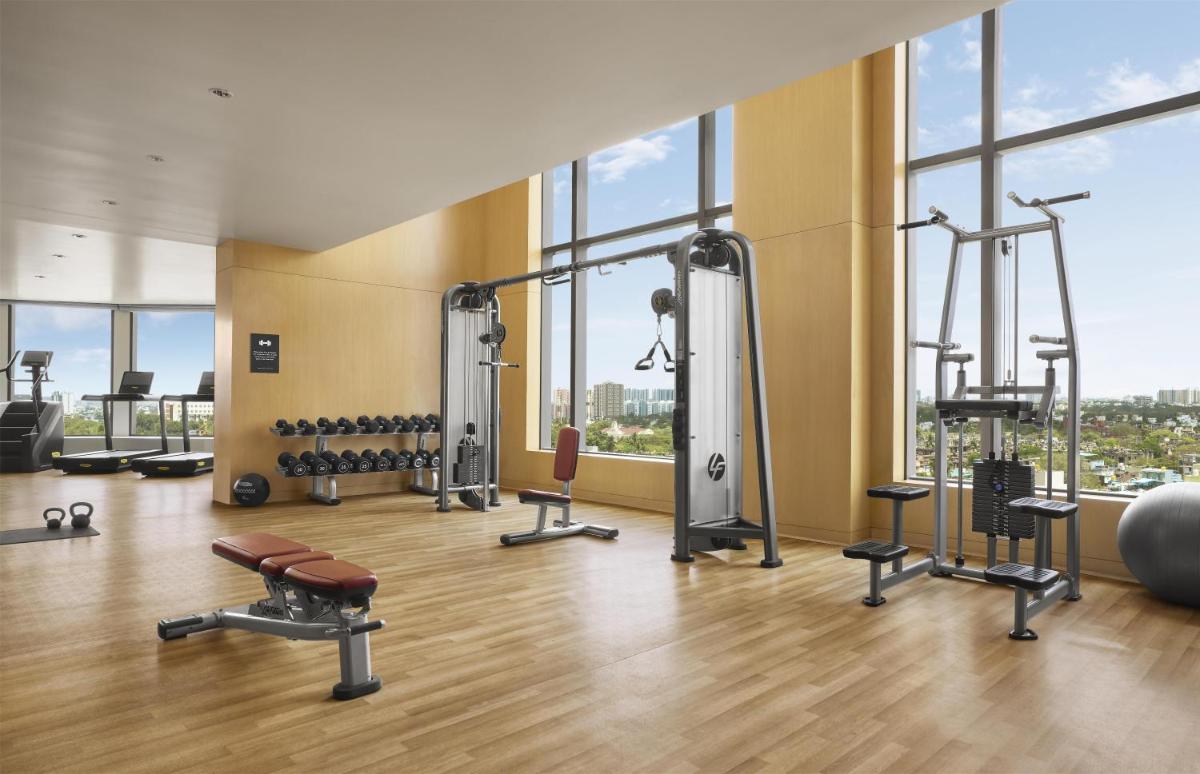 a gym with a lot of exercise equipment and windows at Park Hyatt Chennai in Chennai