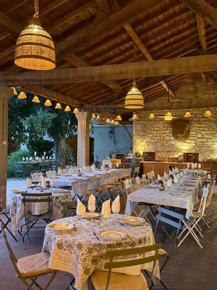 un restaurant avec de longues tables, des chaises et des lumières dans l'établissement HOTEL et APPARTEMENTS DOMAINE DES CLOS - Teritoria, à Beaucaire
