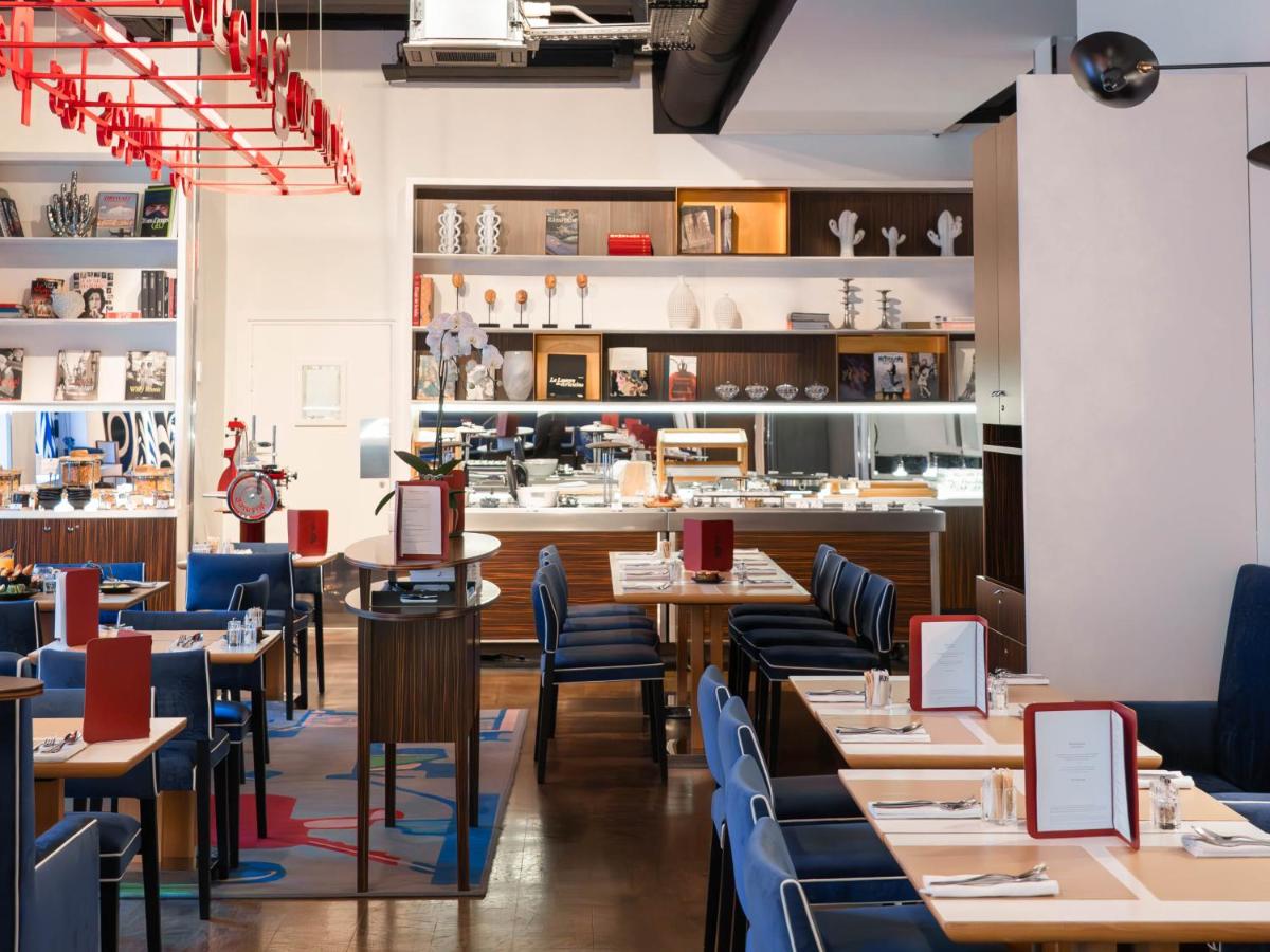 un restaurant avec des tables en bois et des chaises bleues dans l'établissement Hôtel Bel Ami, à Paris