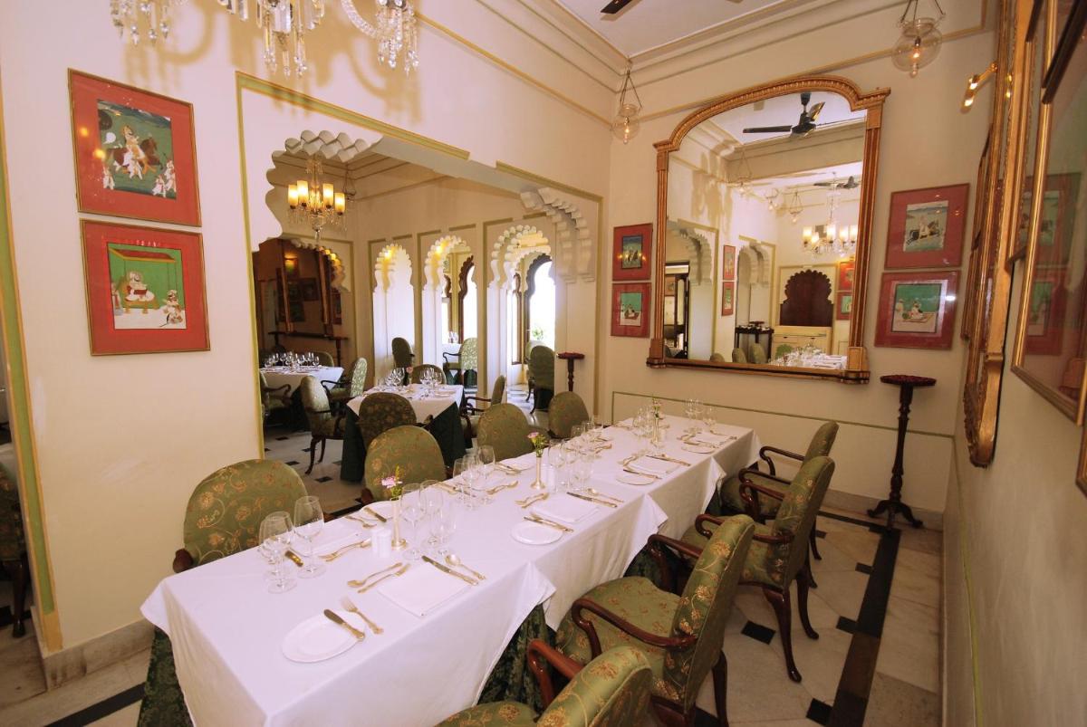 a dining room with white tables and chairs and a mirror at Shiv Niwas Palace by HRH Group of Hotels in Udaipur