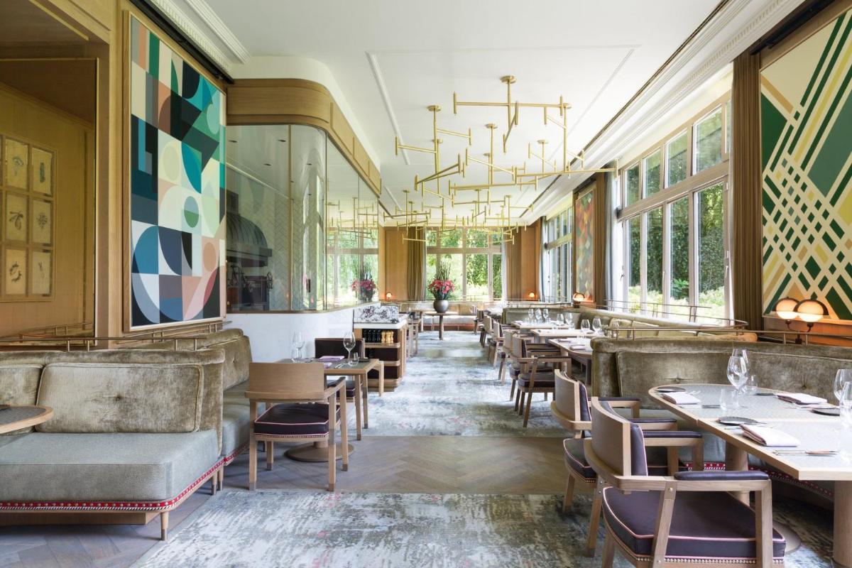 ein Esszimmer mit Tischen, Stühlen und Fenstern in der Unterkunft Brenners Park Hotel & Spa, Oetker Hotels in Baden-Baden