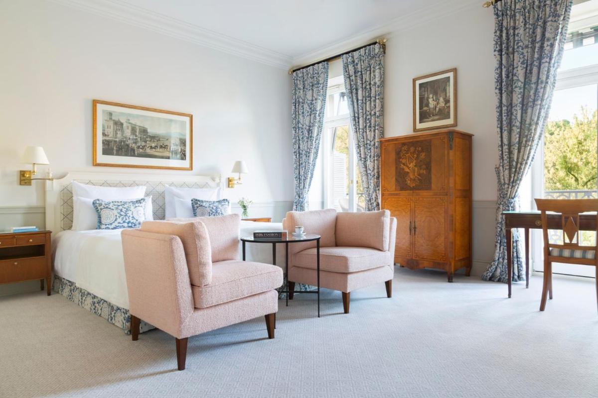 ein Schlafzimmer mit einem Bett, zwei Stühlen und einem Tisch in der Unterkunft Brenners Park Hotel & Spa, Oetker Hotels in Baden-Baden